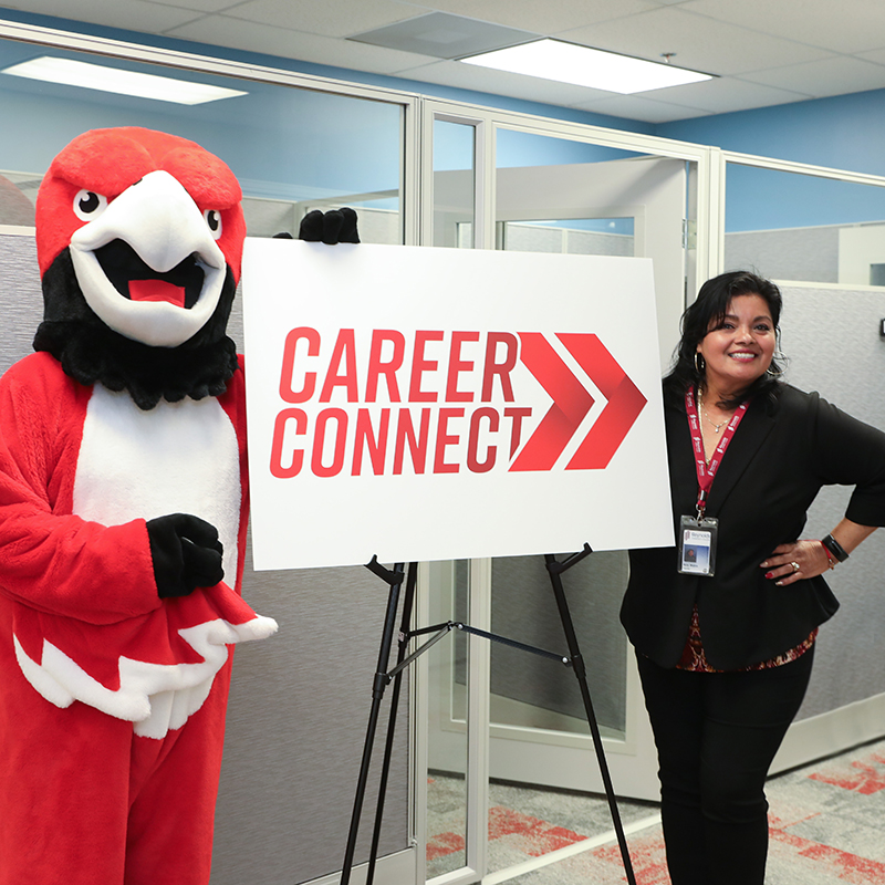 Sarge the Red Hawk stands with a woman at the Career Connect sign